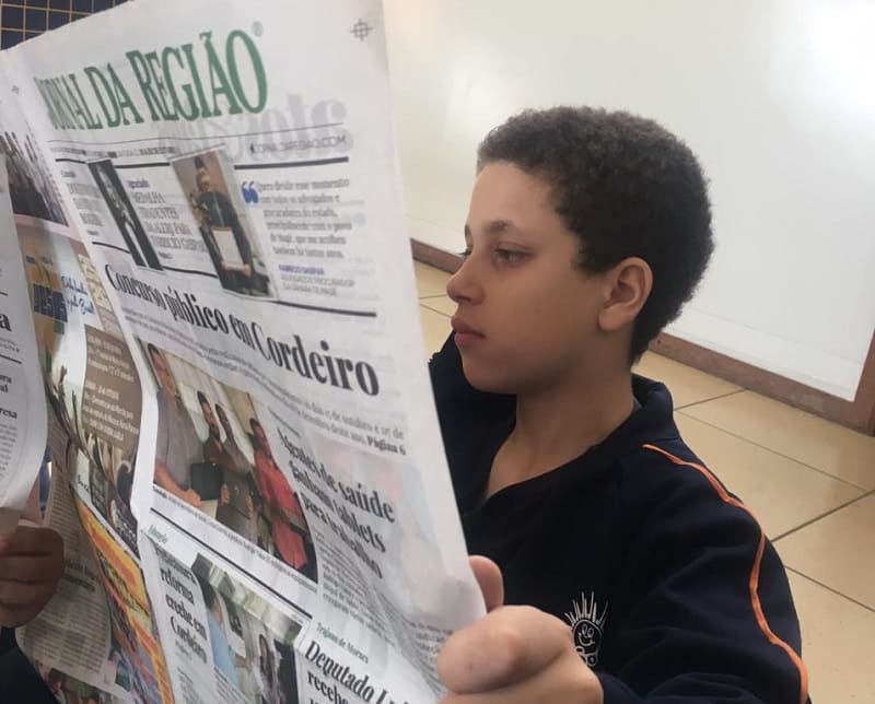 Crianças em Nova Friburgo lendo o Jornal da Região